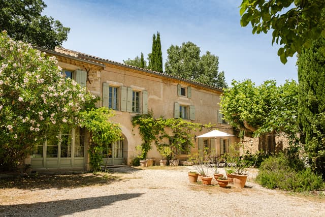 Farmhouse facade and courtyard framed by mature trees
